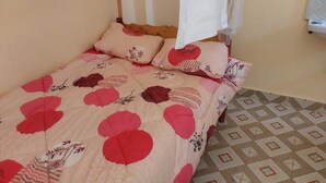 A bed with a floral bedspread and two pillows, a white canopy, and a patterned floor.