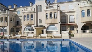 Piscina refletindo um edifício com janelas em arco e varandas.