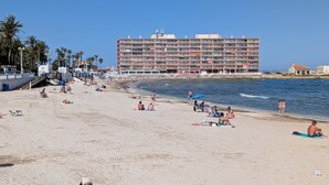 Uma praia com um hotel grande ao fundo.