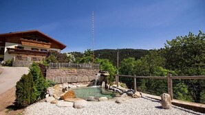Una cabana de muntanya amb paret de pedra, tanca de fusta i cel serè.