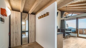 A modern interior with wooden beams, a dining area with a view, and a coat rack.