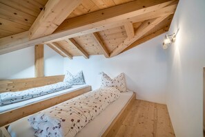 Ein Zimmer mit zwei Holzwetten, weißen Wänden und einer schrägen Decke mit freiliegenden Balken.