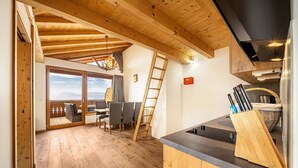 A wooden interior with a dining area, kitchen counter, and a view through a glass door. - Apartment "Eggerhof Fernblick" with Mountain View, Lake Access & Wi-Fi (Verano)