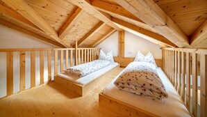 A wooden loft bedroom with two beds, a wooden ceiling, and a sloped roof. - Apartment "Eggerhof Fernblick" with Mountain View, Lake Access & Wi-Fi (Verano)