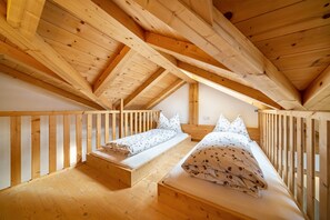 Un dormitorio estilo altillo de madera con dos camas, techo de madera y techo inclinado.