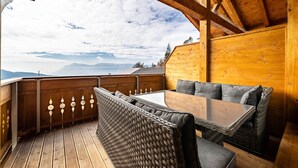 A wooden deck with a table and seating, overlooking a mountainous landscape. - Apartment "Eggerhof Fernblick" with Mountain View, Lake Access & Wi-Fi (Verano)