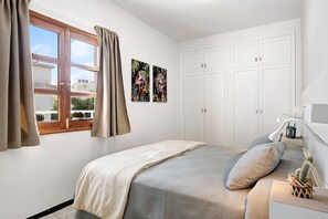 A bedroom with a bed, curtains, a window, a wardrobe, and two wall art pieces. - Vacation Apartment 'Apartamento La Estrella 4' with Balcony and Wi-Fi (Arrecife)