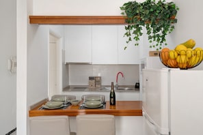 A small kitchen with white cabinets, a wooden countertop, a sink, a refrigerator, and a bowl of fruit on the counter. - Vacation Apartment 'Apartamento La Estrella 4' with Balcony and Wi-Fi (Arrecife)