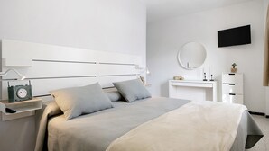 Un dormitorio moderno con cama, mesita de noche, lámpara y un televisor de pantalla plana montado en la pared.