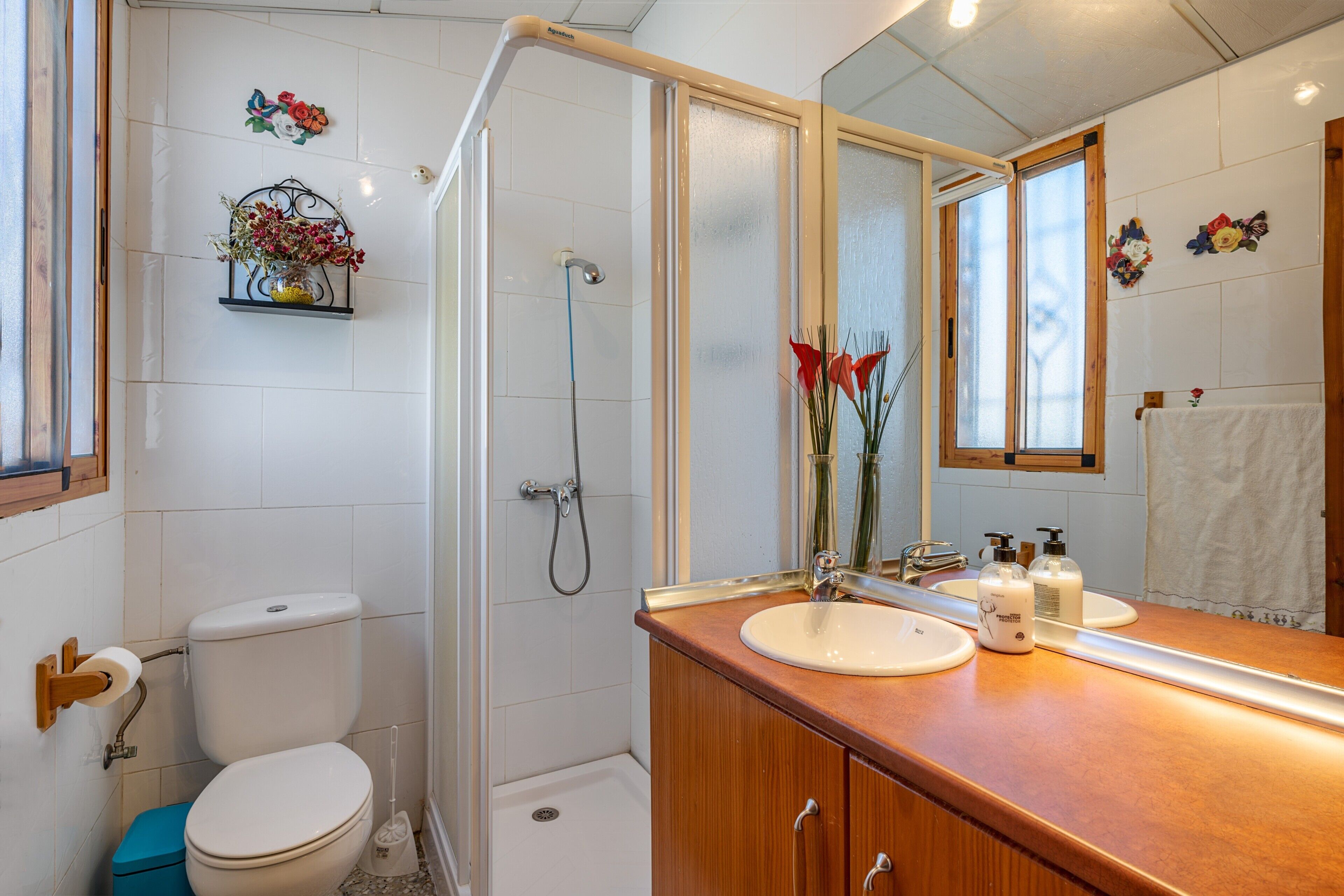 A bathroom with a toilet, shower, sink, and mirror.