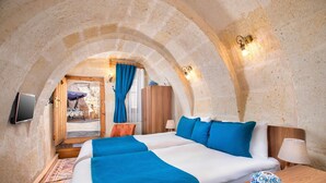 Un dormitorio con dos camas, una mesita de noche de madera, una lámpara y un jarrón decorativo.