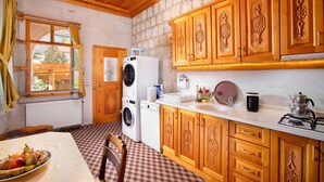Una cocina con armarios de madera, lavadora, estufa y una mesa con fruta.