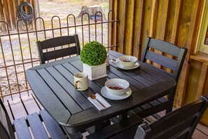 A table set with a bowl of cereal, a cup, and a spoon, with a small potted plant on the table.