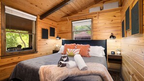 Un dormitorio de cabaña de madera con cama, almohadas y mesita de noche.