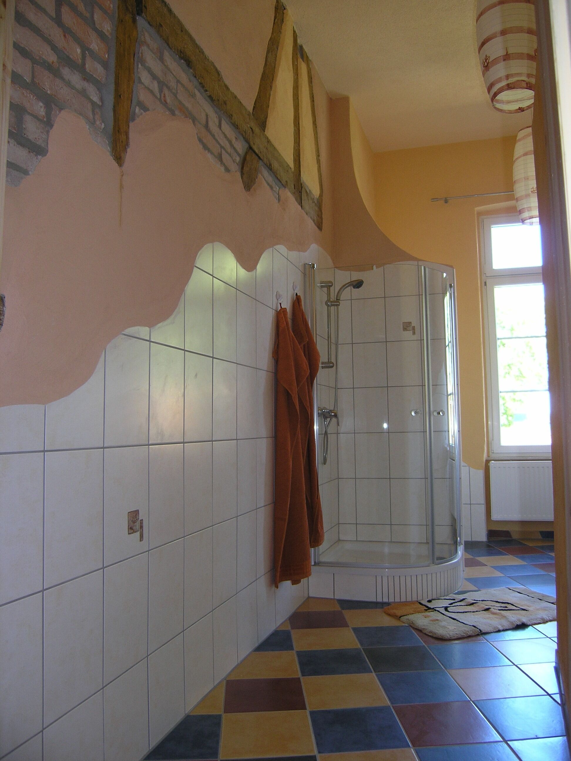 A bathroom with a shower, tiled walls, and a checkered floor.