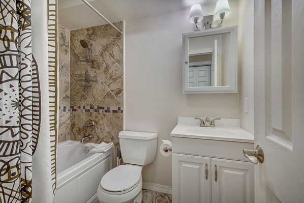 A bathroom with a bathtub, toilet, and sink.