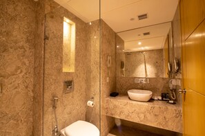 A modern bathroom with a glass-enclosed shower, a marble sink, and a vanity with a mirror. - The Pristine Hotel Kanpur (Kanpur)
