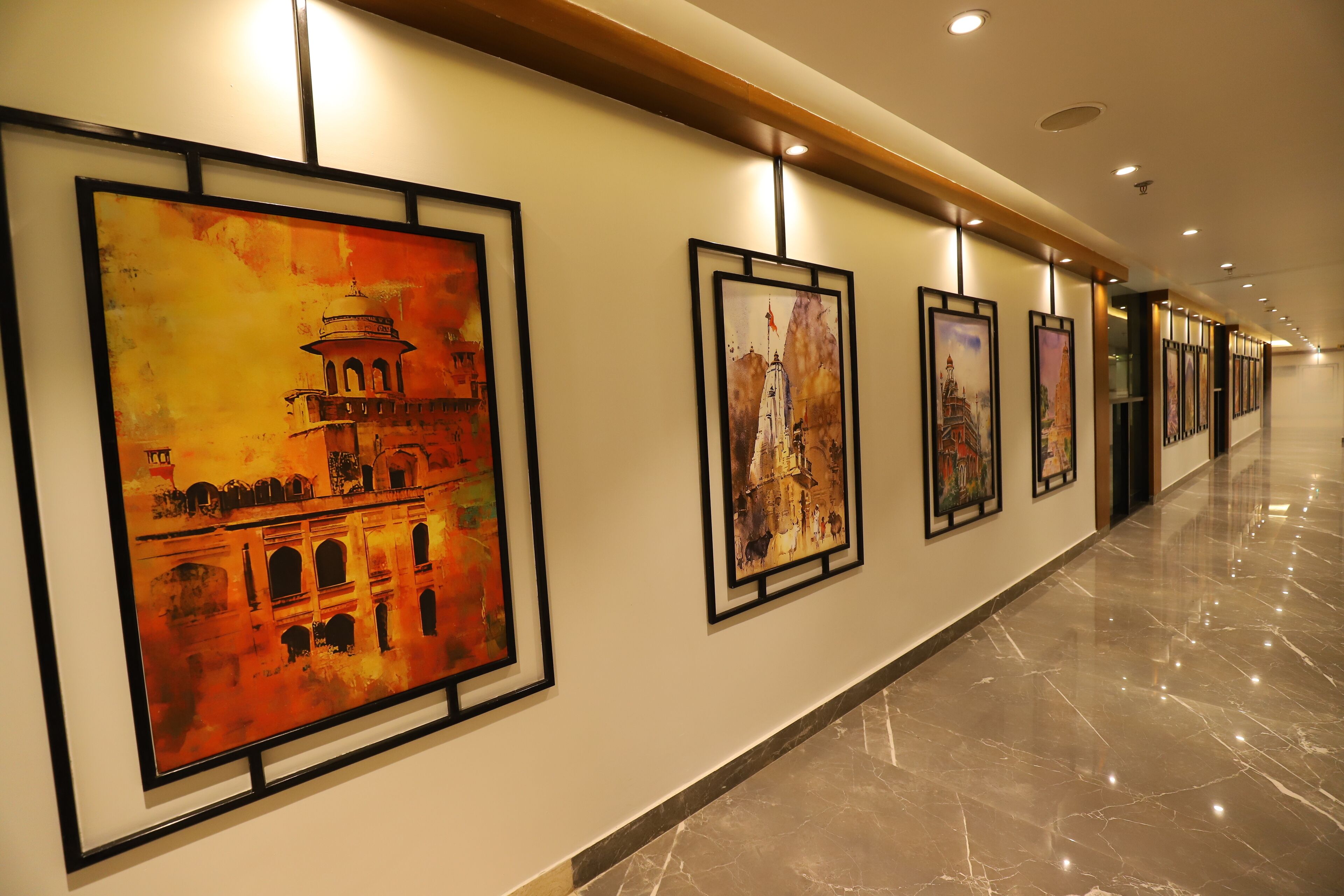 A corridor with framed artworks on the walls and a polished marble floor.