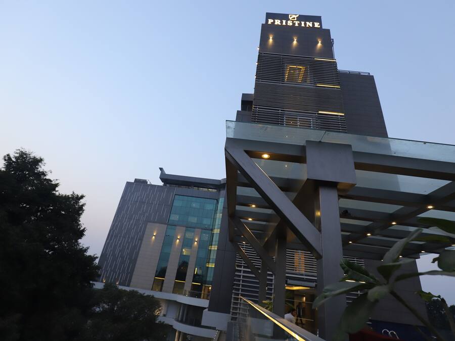 A modern building with the sign 'PRISTINE' at the top. It features a glass facade and a metal structure in the foreground.