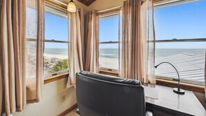 Une chambre avec vue sur la plage, un bureau et une chaise.