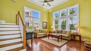 A living room with a wooden staircase, two sofas, a coffee table, and a floor lamp. - Welcome to Good Day Sunshine! (St. George Island)