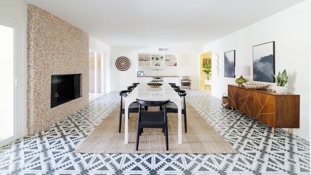 A modern dining area with a central table, chairs, and a decorative wall.