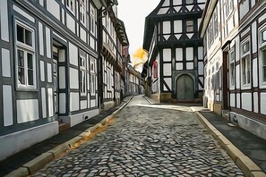 A narrow cobblestone street flanked by traditional half-timbered buildings with a central doorway and a small archway. - Modern apartment with WiFi in the old town (near the market square) (Goslar)