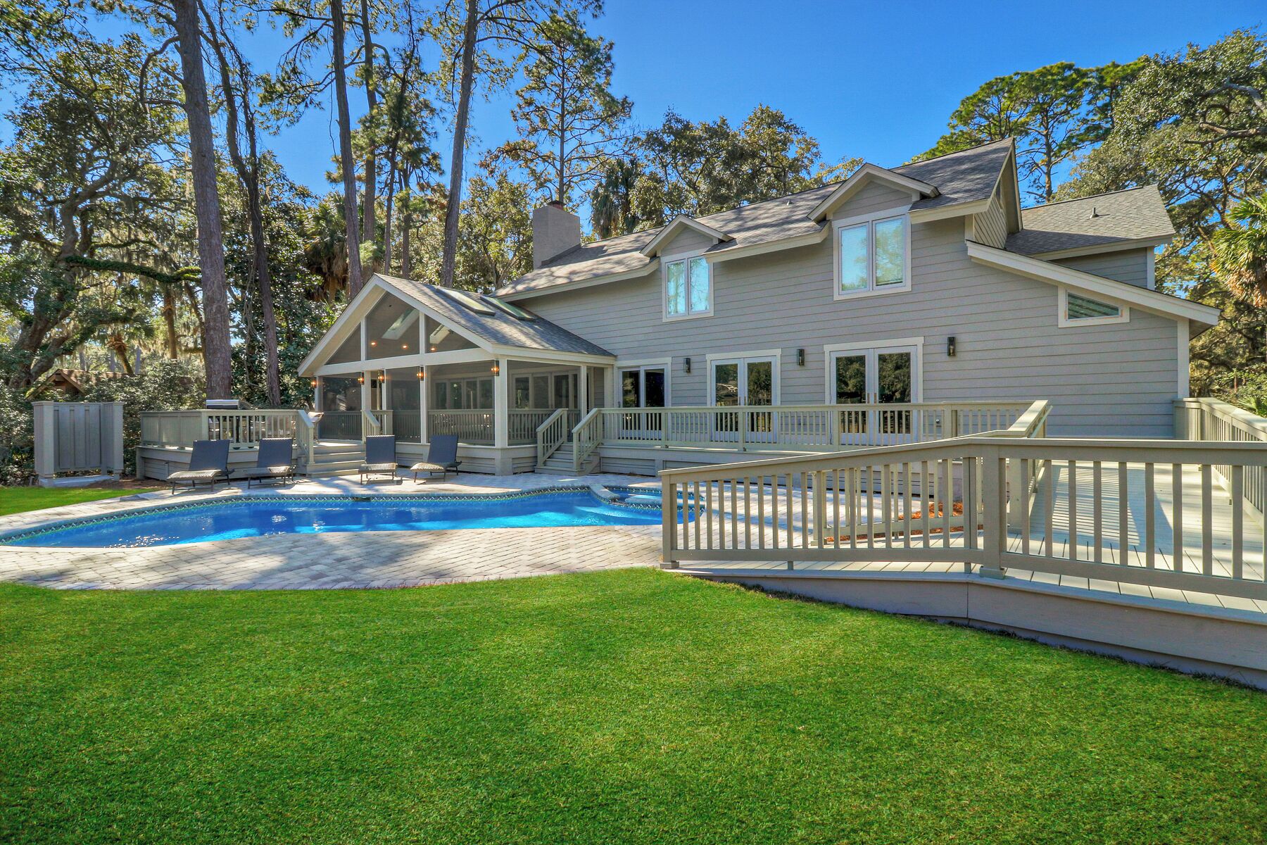 A two-story house with a covered patio, a swimming pool, and a well-maintained lawn.