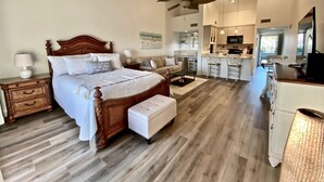 A bedroom with a wooden bed, a nightstand, a bedside table, a sofa, a coffee table, and a ceiling fan.