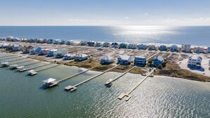 An aerial view of a coastal residential area with houses and piers extending into the water.