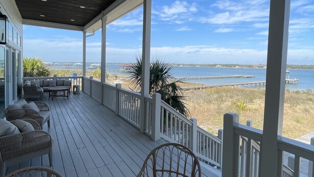A covered outdoor deck with a view of the beach and ocean.