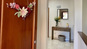 A wooden door with a floral decoration, a console table with a vase, and a mirror above it. - Villa Over the 5th Green (San Bartolomé de Tirajana)