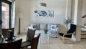 A modern living room with a sofa, two armchairs, a coffee table, and a dining area with chairs and a glass table. - Villa Over the 5th Green (San Bartolomé de Tirajana)