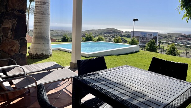 A patio area with a pool, outdoor furniture, and a view of a residential area and hills. - Villa Over the 5th Green (San Bartolomé de Tirajana)