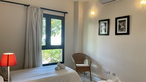 Une chambre d’hôtel avec deux lits, une chaise, une lampe et une fenêtre avec des rideaux.