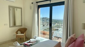 Une chambre d’hôtel avec un lit, une chaise, une table et un balcon offrant une vue.