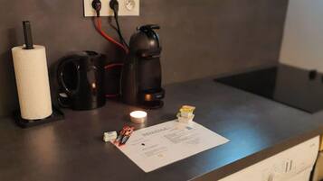 Een aanrecht met een koffiezetapparaat, een rol keukenpapier en een klein doosje zakdoekjes.