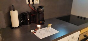 Una encimera de cocina con una cafetera, un rollo de toallas de papel y una pequeña caja de pañuelos.
