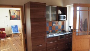 Een kleine keuken met houten kastjes, een magnetron en een spoelbak.