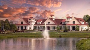 Un hotel grande de varios pisos con un patio central, una fuente y un lago.