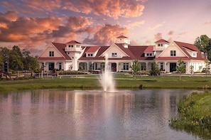 A large, multi-story hotel with a central courtyard, a fountain, and a lake.
