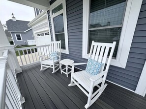 A porch with two white rocking chairs and a small table.