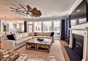 A living room with a sectional sofa, a wooden coffee table, a fireplace, and a ceiling fan. - Bayside * 5BR New Luxury House (Selbyville)