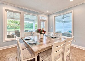 A dining area with a wooden table, white chairs, and a vase of flowers. - Bayside * 5BR New Luxury House (Selbyville)