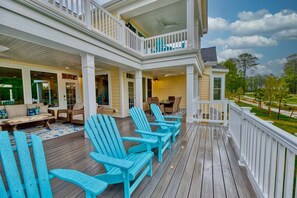 A covered porch with Adirondack chairs, a dining area with a table and chairs, and a view of the surrounding landscape. - Bayside * 5BR New Luxury House (Selbyville)