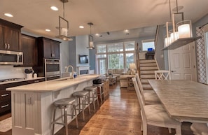 A modern kitchen with a central island, bar stools, and a dining area with a long table.
