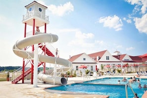 A water park with a multi-lane water slide, a pool, and a lifeguard tower.