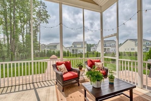 A covered patio with wicker furniture, a table, and potted plants.