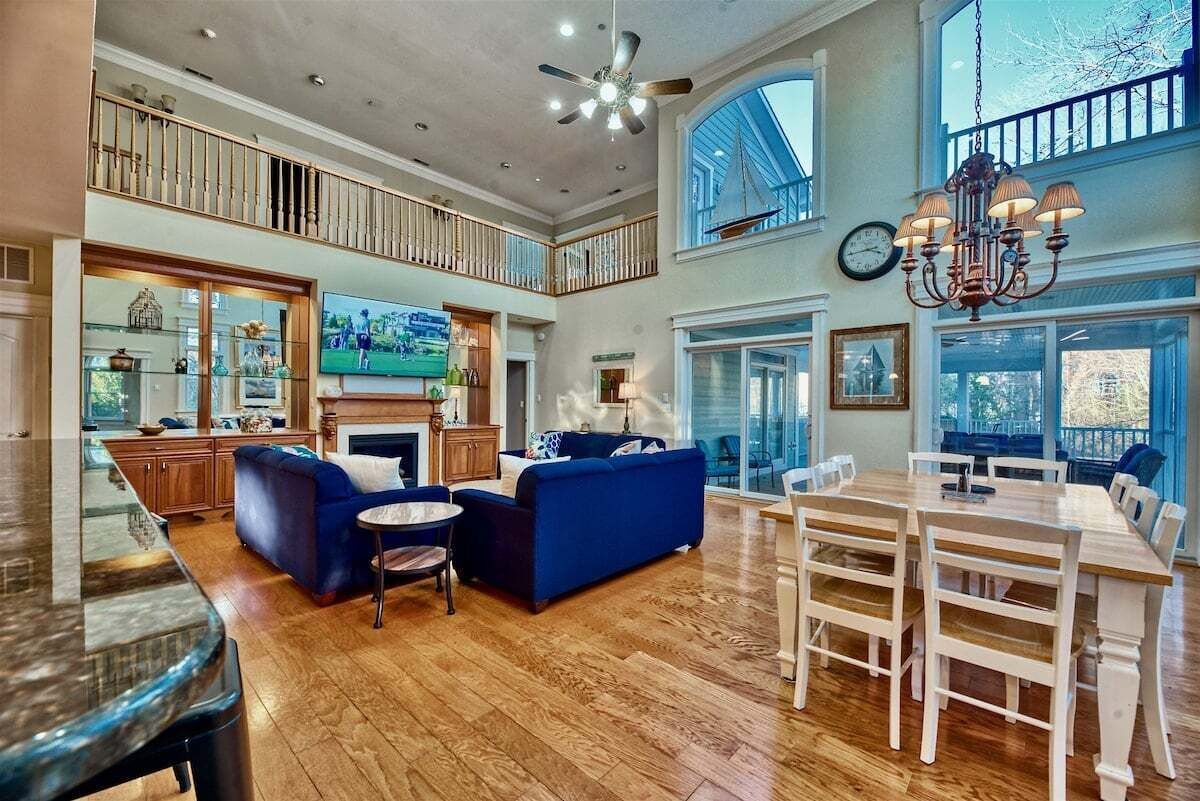 A spacious living room with a fireplace, a dining area, and a balcony.