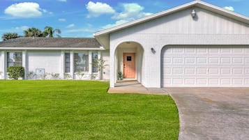 A single-story house with a garage, a well-maintained lawn, and a clear sky.